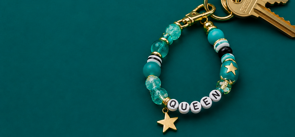 Personalized beaded keychain with turquoise beads, white letter beads spelling QUEEN, and gold star charm.